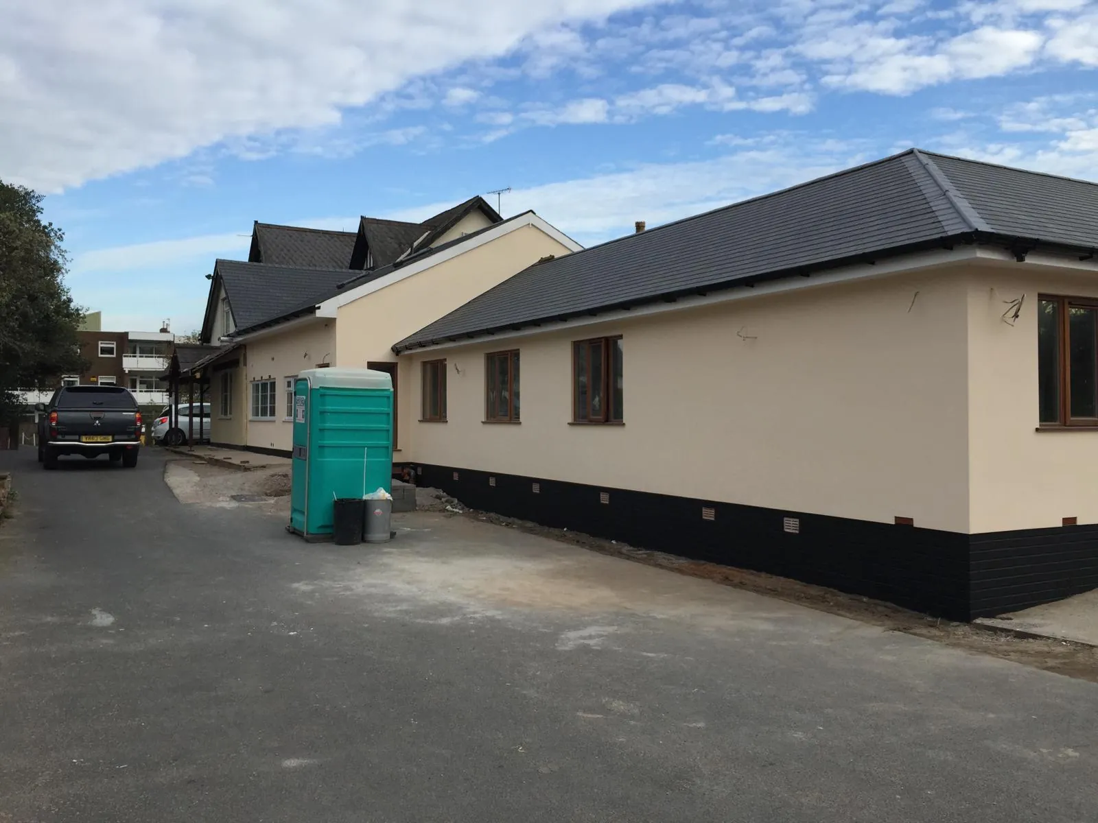 Long bungalow elevation with cream coating and dark plinth