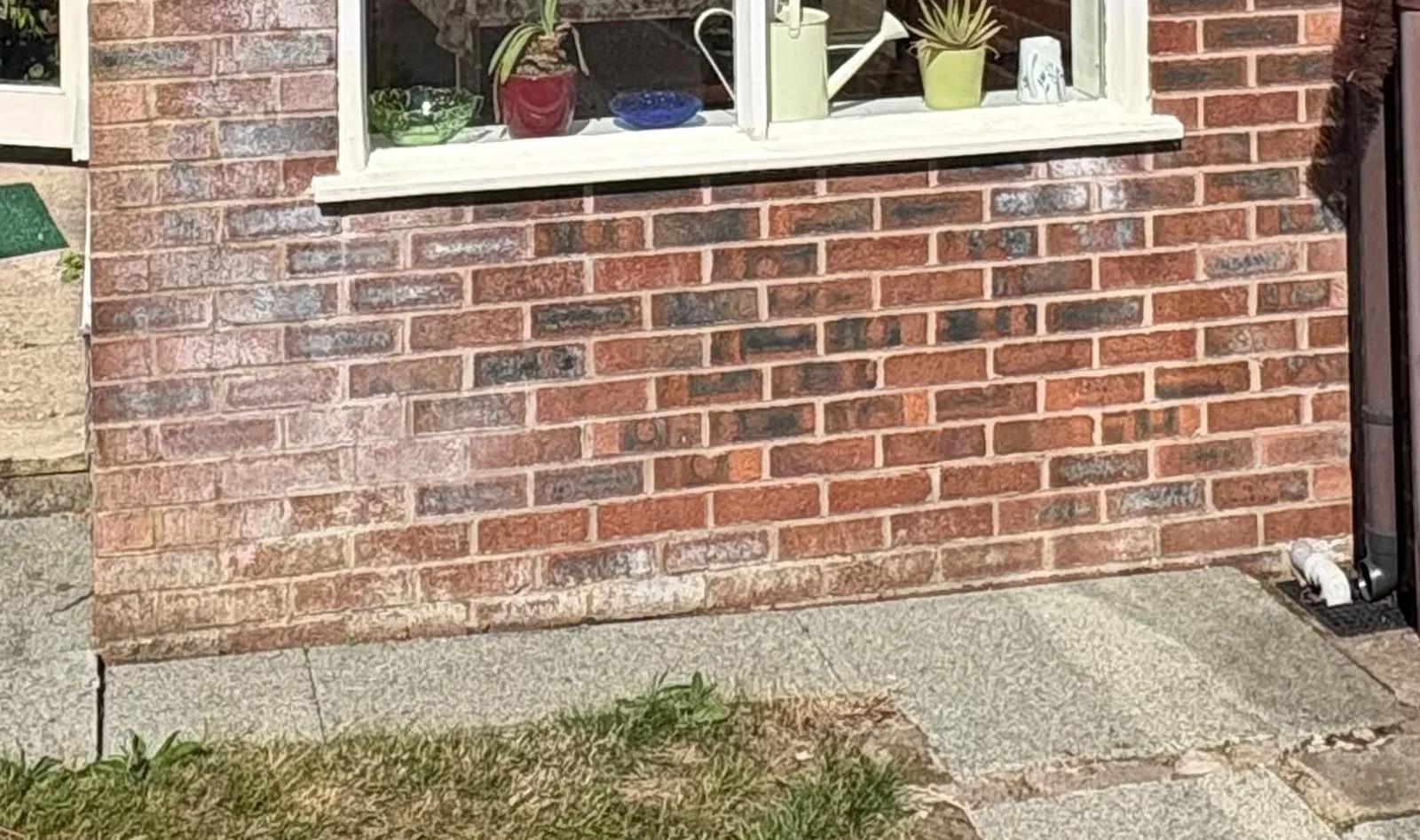 Brickwork below a window sill showing white salt staining on the weather elevation